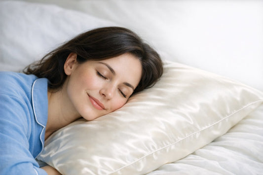A woman with fair skin resting on a smooth ivory mulberry silk pillowcase in soft morning light, eyes closed and skin smooth without pillow creases
