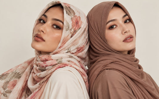 Two women wearing silk hijabs, one in a soft pink floral print and one in plain mocha brown
