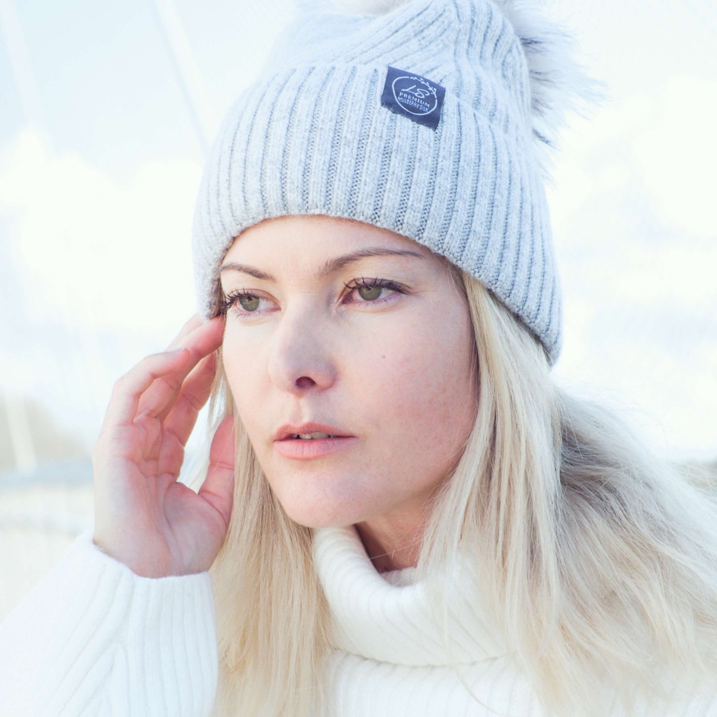 Woman outdoors wearing light grey silk-lined pom pom beanie – LS Silk NZ