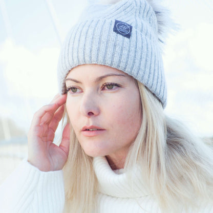 Woman outdoors wearing light grey silk-lined pom pom beanie – LS Silk NZ