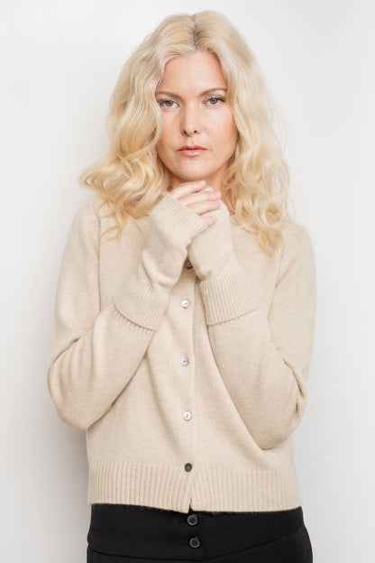 Woman wearing beige cashmere fingerless gloves, hands at chest – Love Cashmere NZ