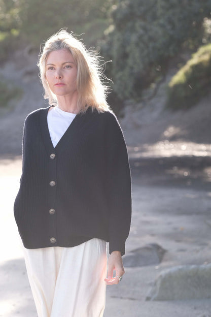 Woman in black cashmere cardigan open over white tee at beach – Love Cashmere NZ