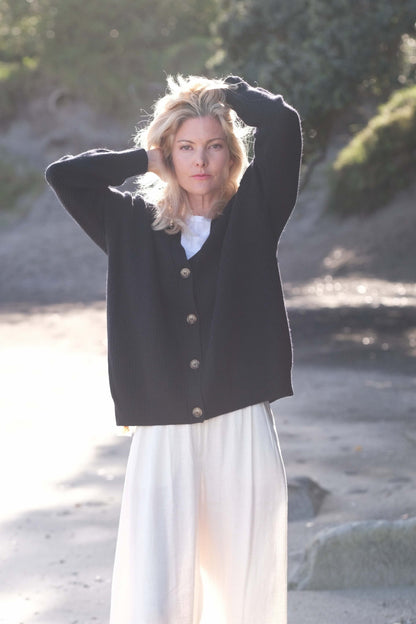 Model at the beach in black cashmere cardigan, arm raised – Love Cashmere NZ
