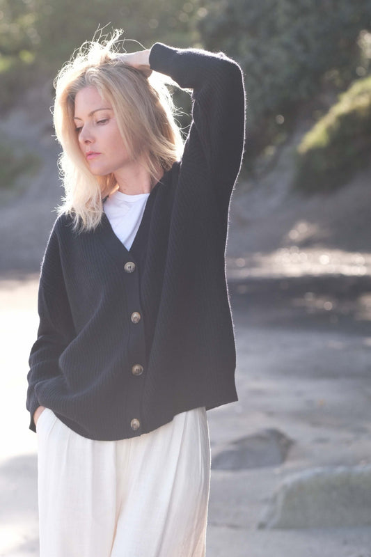 Woman at the beach in black relaxed-fit cashmere cardigan – Love Cashmere NZ