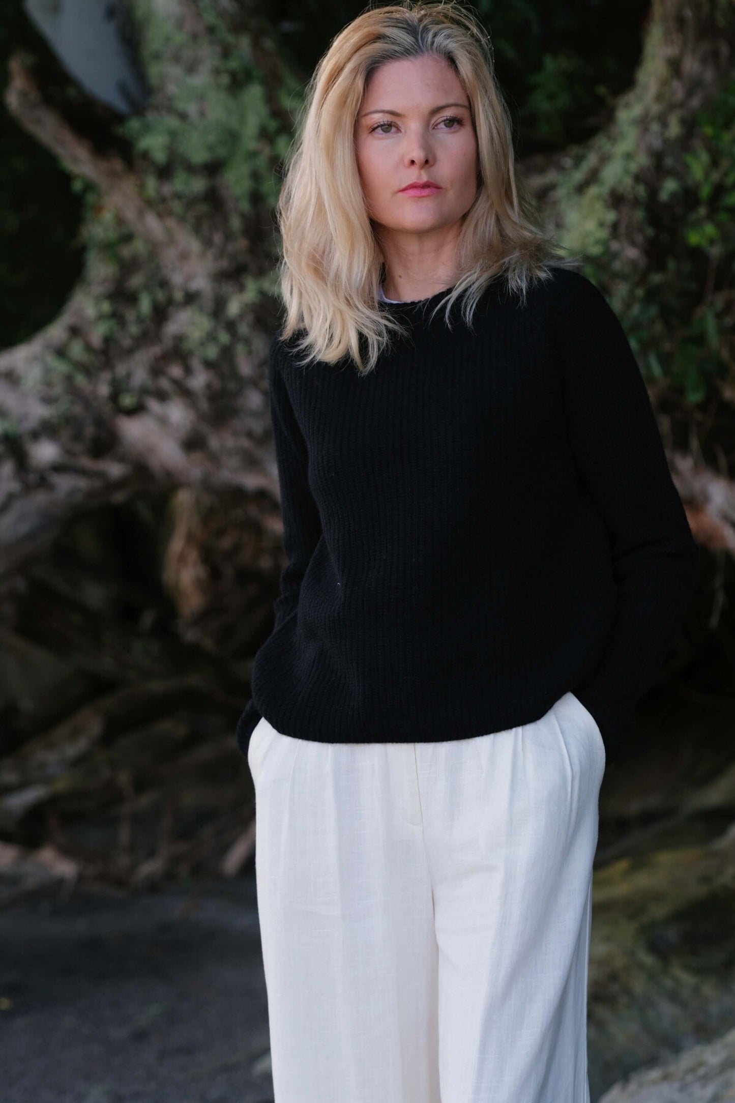 Woman outdoors in black fisherman cashmere sweater, white pants – Love Cashmere NZ