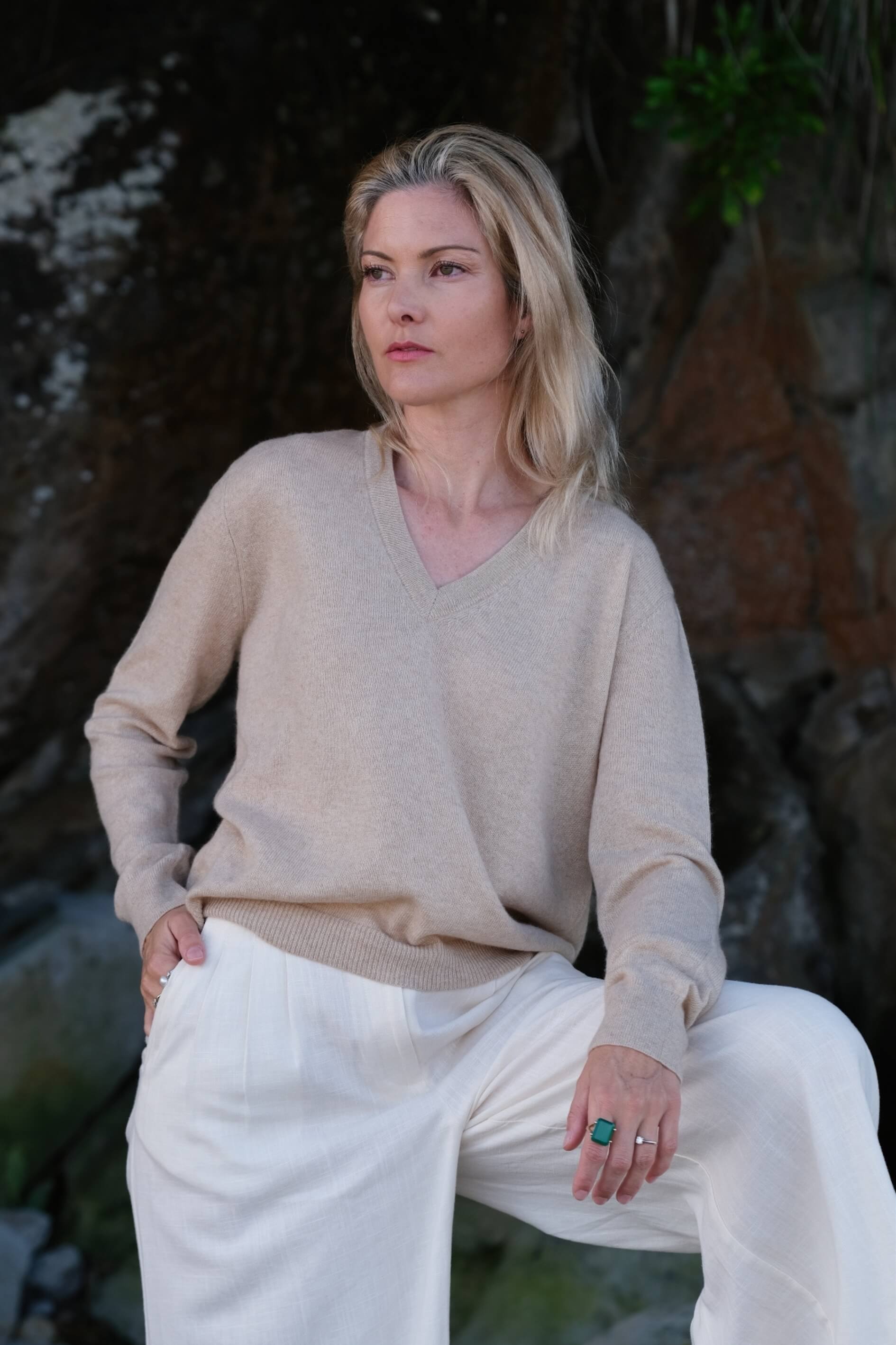 Woman at dusk beach in beige cashmere V-neck and white pants – Love Cashmere NZ