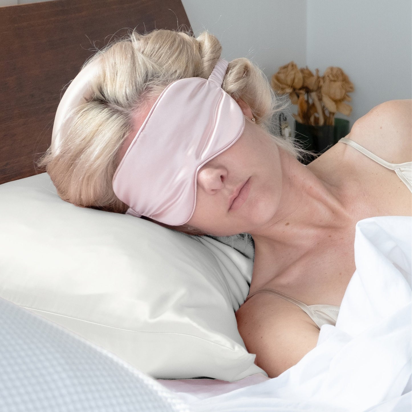 Woman sleeping on ivory silk pillowcase wearing a pink silk eye mask – LS Silk NZ