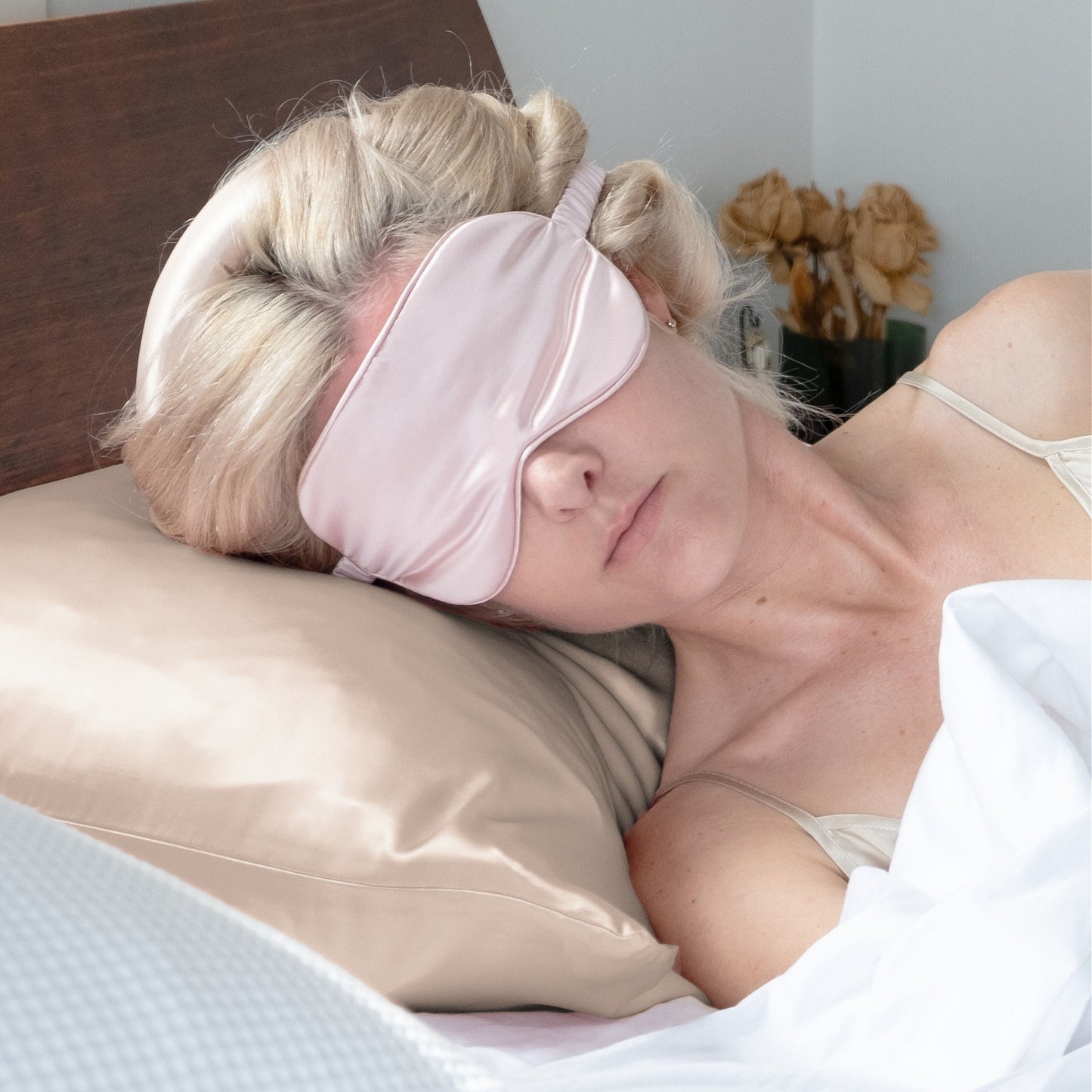 Woman sleeping on champagne silk pillowcase wearing a pink silk eye mask – LS Silk NZ