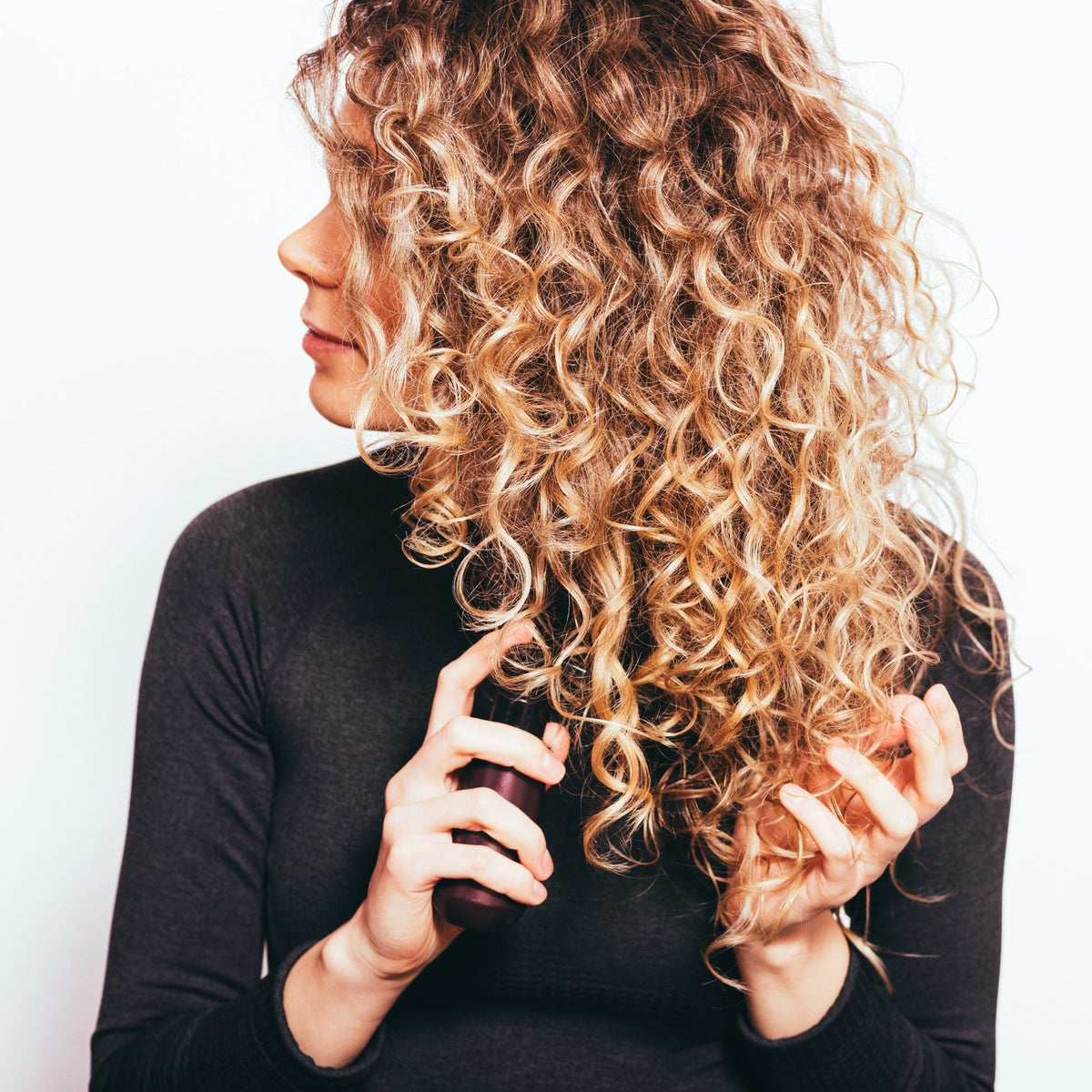 Woman with long, natural curly hair running her fingers through her curls