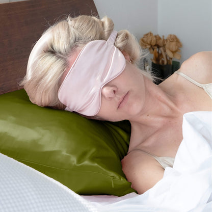 Woman sleeping on olive green silk pillowcase wearing a pink eye mask – LS Silk NZ