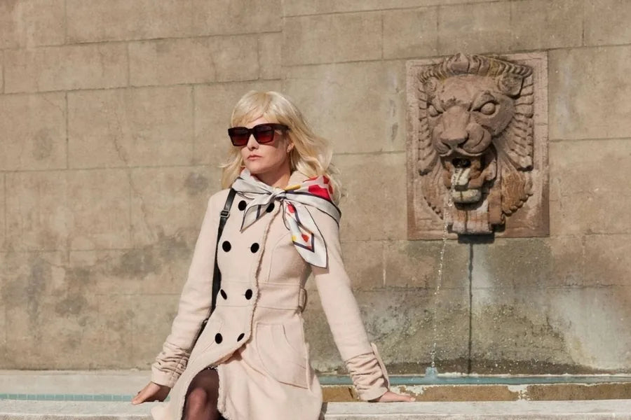 A woman wearing a printed silk scarf at the neck of a cream coat